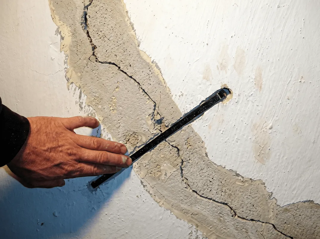 A wall with a large crack is being inspected by a professional in Salt Lake City, UT